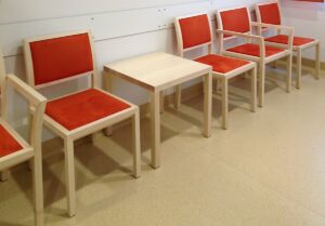 Wartezimmer mit Holzstuehlen und Tisch
